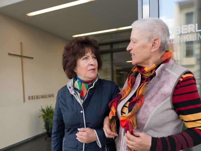 Zwei ältere Damen sprechen im Eingangsbereich über die Klinik