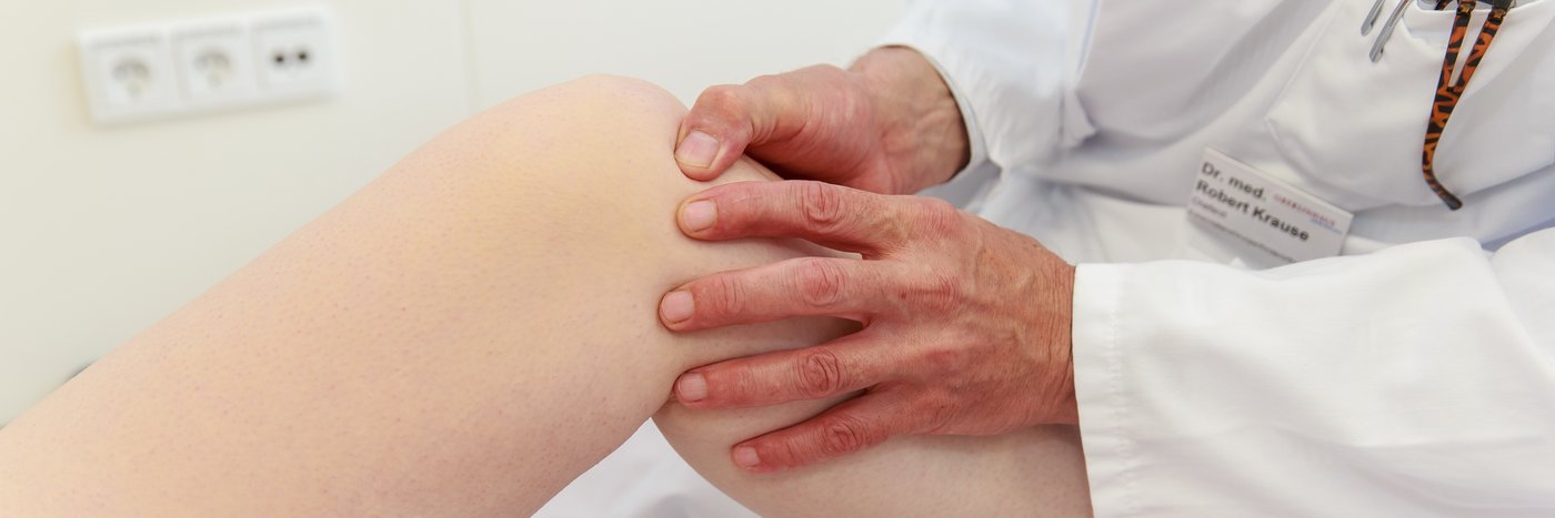 Ein Arzt überprüft das Knie eines Patienten