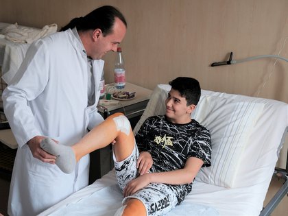ein Arzt hilft einem Jugendlichen bei der Bewegung seines Beins.